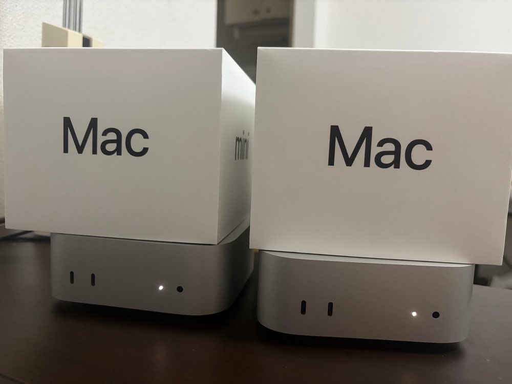 两台全新 Mac mini M6，包装盒放在机身上方，摆在桌面上